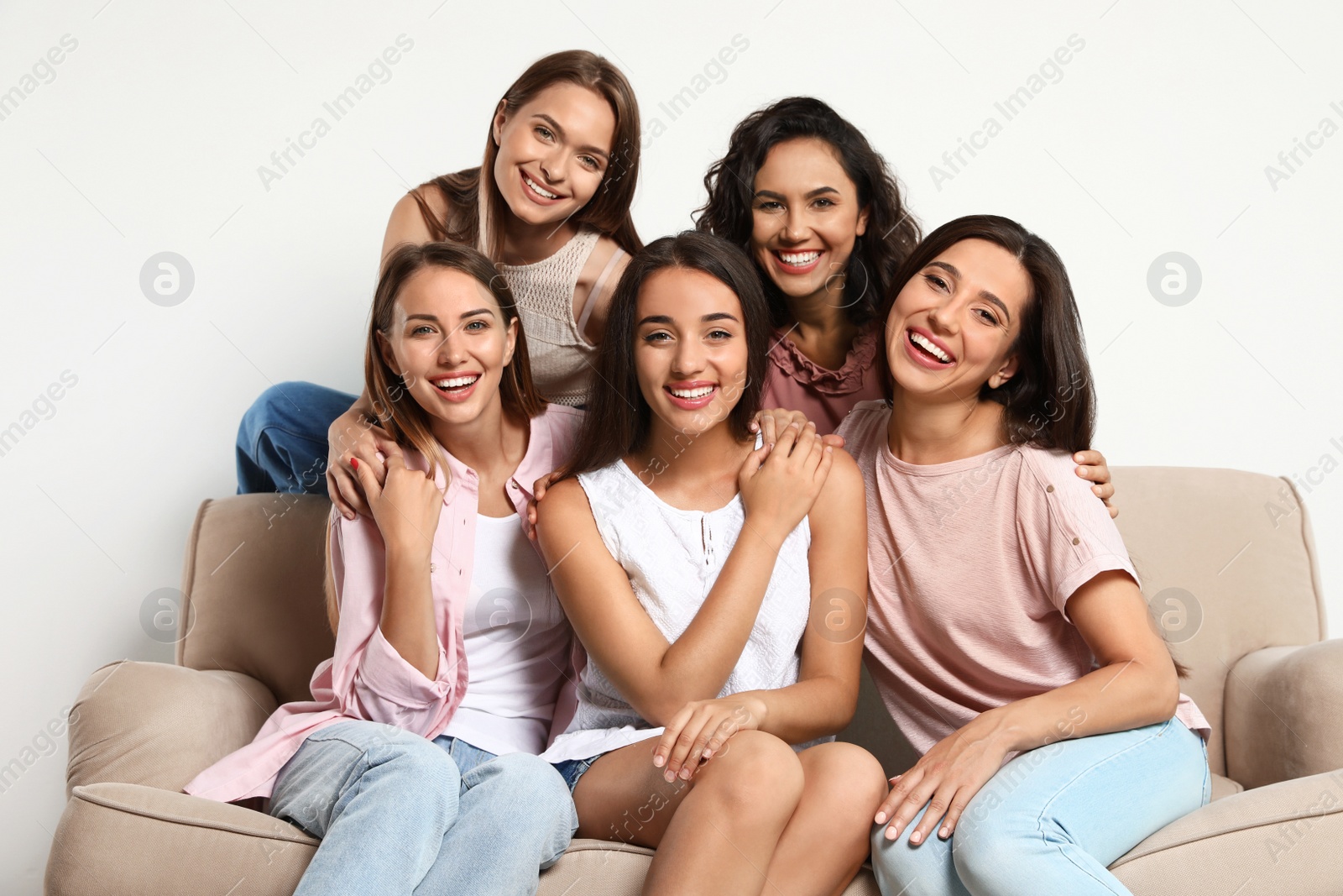 Photo of Happy women sitting on sofa near white wall. Girl power concept