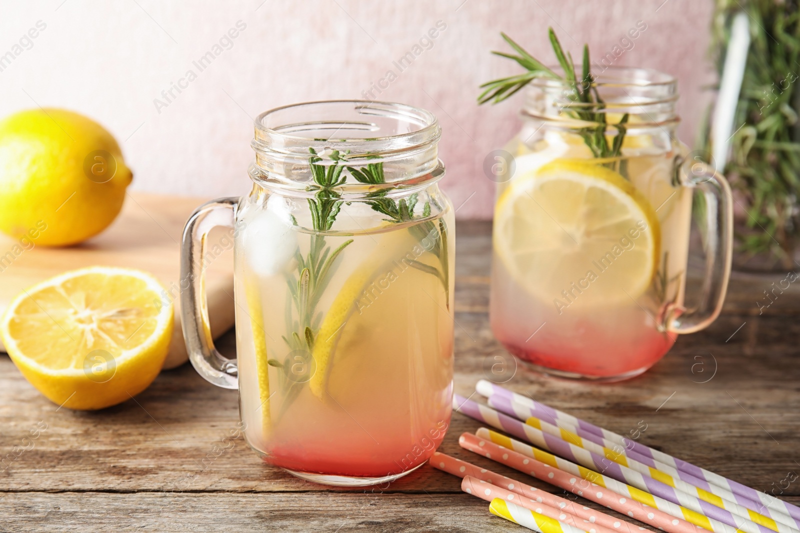 Photo of Refreshing lemon cocktail with rosemary in mason jars on table