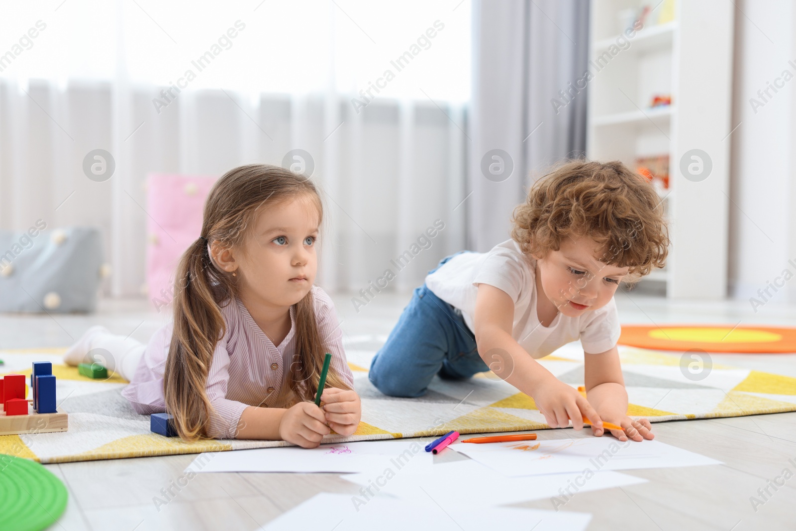 Photo of Cute little children drawing on floor in kindergarten