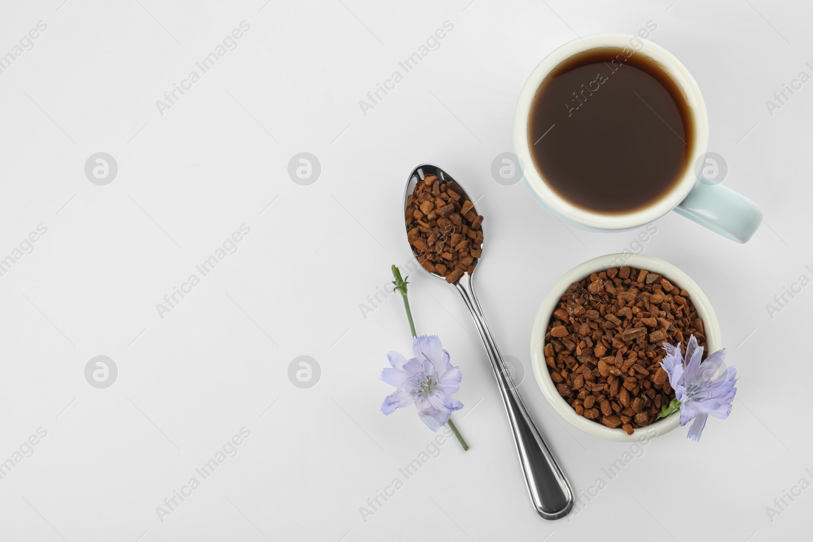 Photo of Cup of delicious chicory drink, granules and flowers on white background, top view