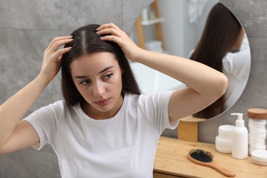 Photo of Woman examining her hair and scalp at home. Dandruff problem