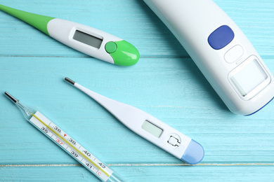 Photo of Different thermometers on light blue wooden table, flat lay