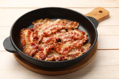 Delicious bacon slices in frying pan on white wooden table