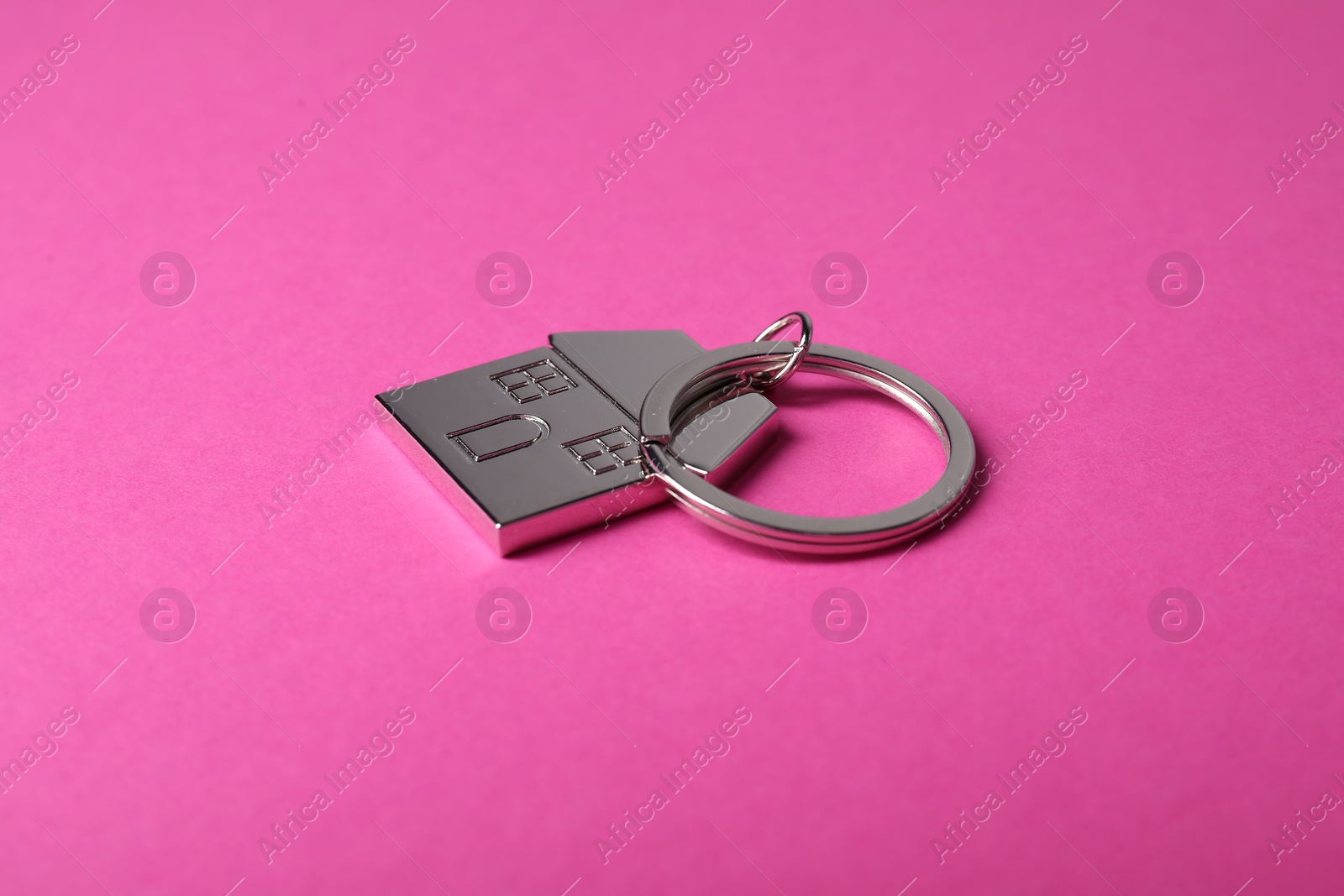 Photo of Metallic keychain in shape of house on bright pink background