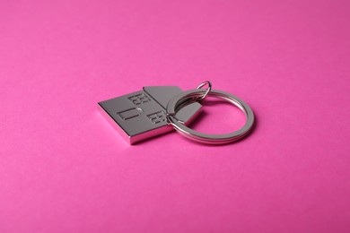 Metallic keychain in shape of house on bright pink background