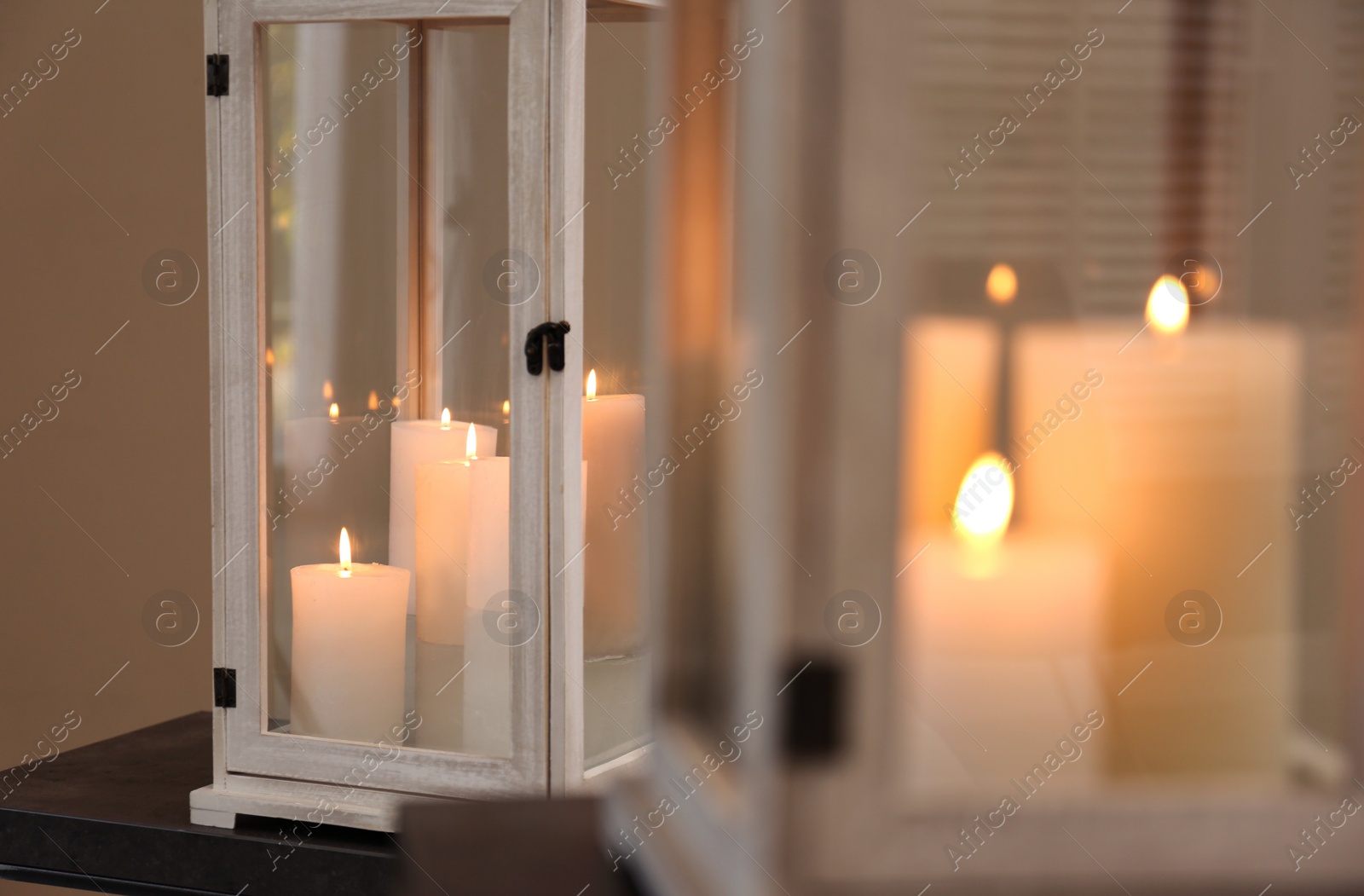 Photo of Decorative lantern with candles on stand, closeup. Interior element