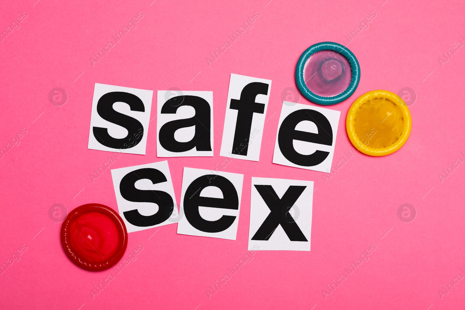 Photo of Colorful condoms and words SAFE SEX on pink background, flat lay