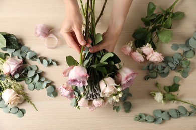 Photo of Florist creating beautiful bouquet at table, top view