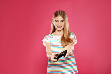 Teenage girl playing video games with controller on color background