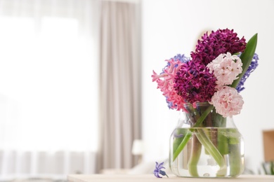 Photo of Beautiful hyacinths in glass vase on table indoors, space for text. Spring flowers