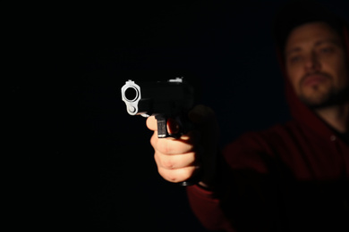 Man holding gun on dark background, focus on hand