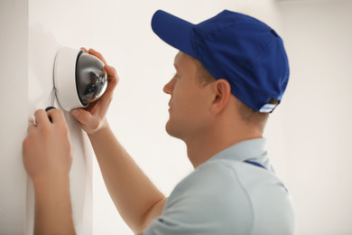 Technician installing CCTV camera on wall, closeup