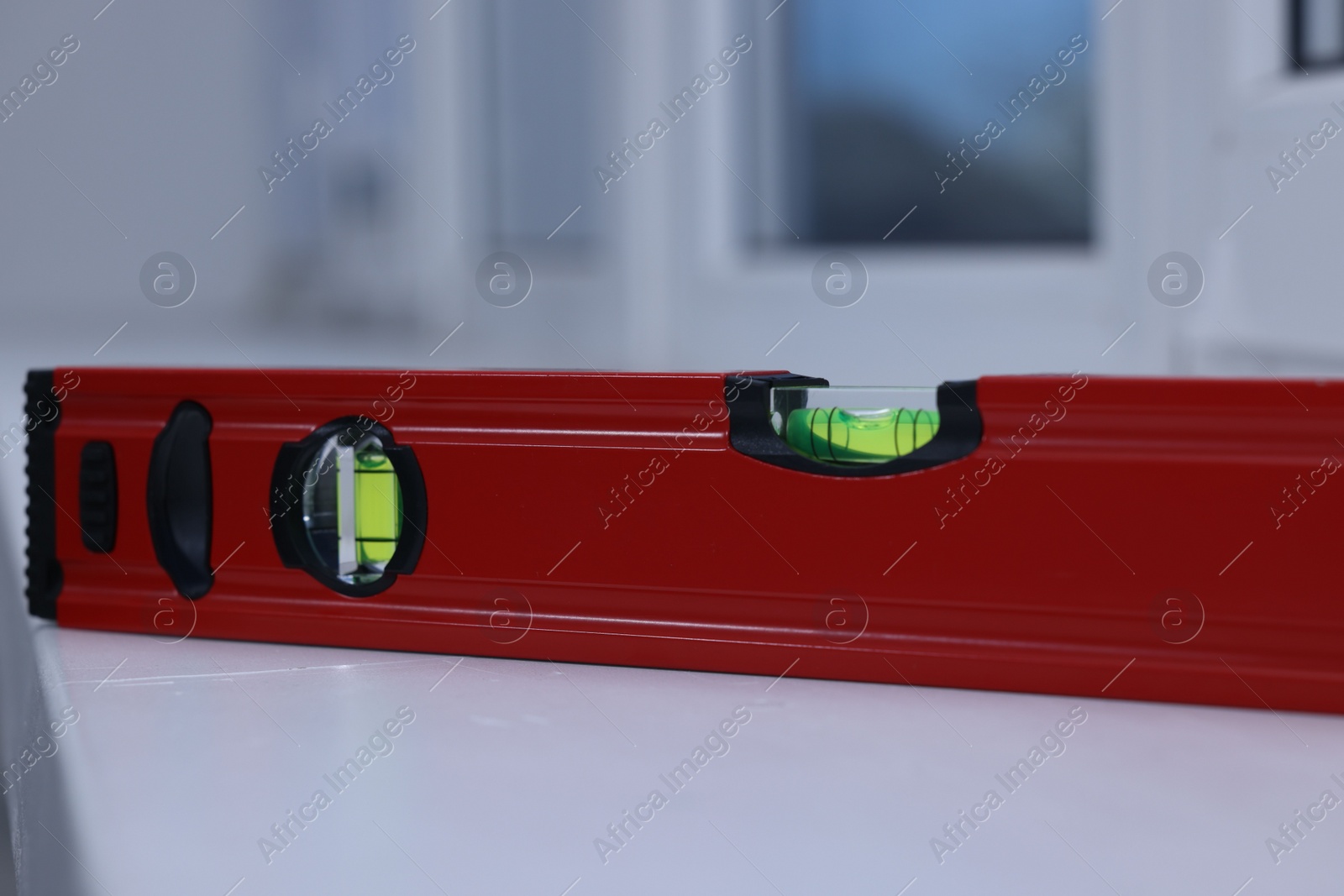 Photo of Red building level on white windowsill indoors, closeup