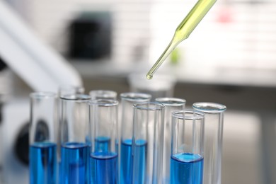 Laboratory analysis. Dripping liquid into test tubes indoors, closeup