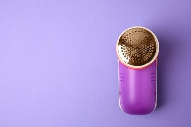 Photo of Modern fabric shaver on violet background, top view. Space for text