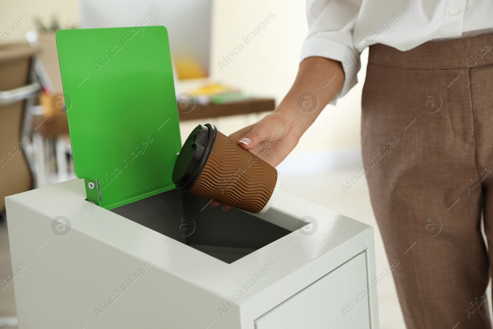 Photo of Woman throwing coffee cup into recycling bin at office, closeup