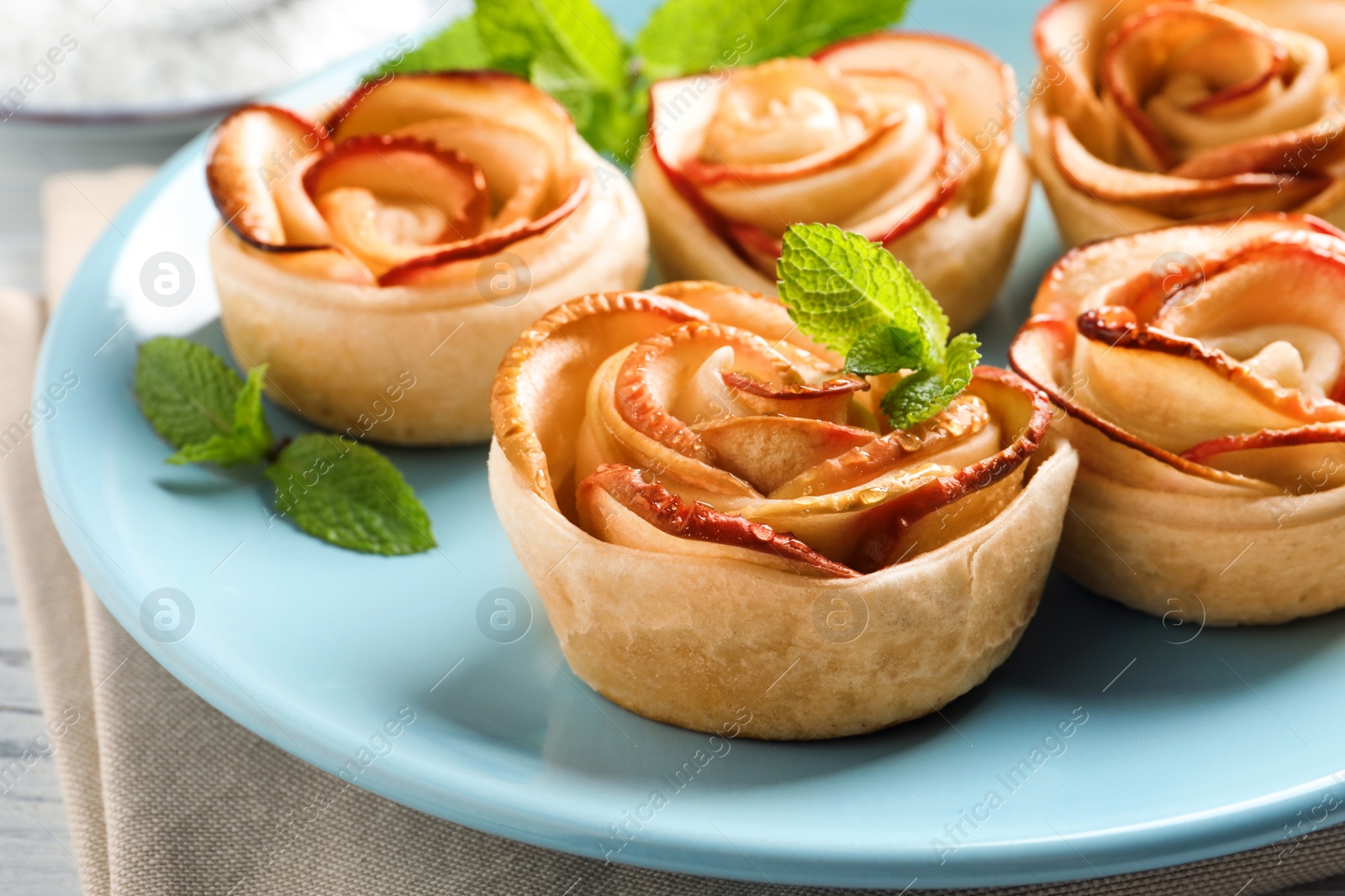 Photo of Freshly baked apple roses on plate, closeup. Beautiful dessert