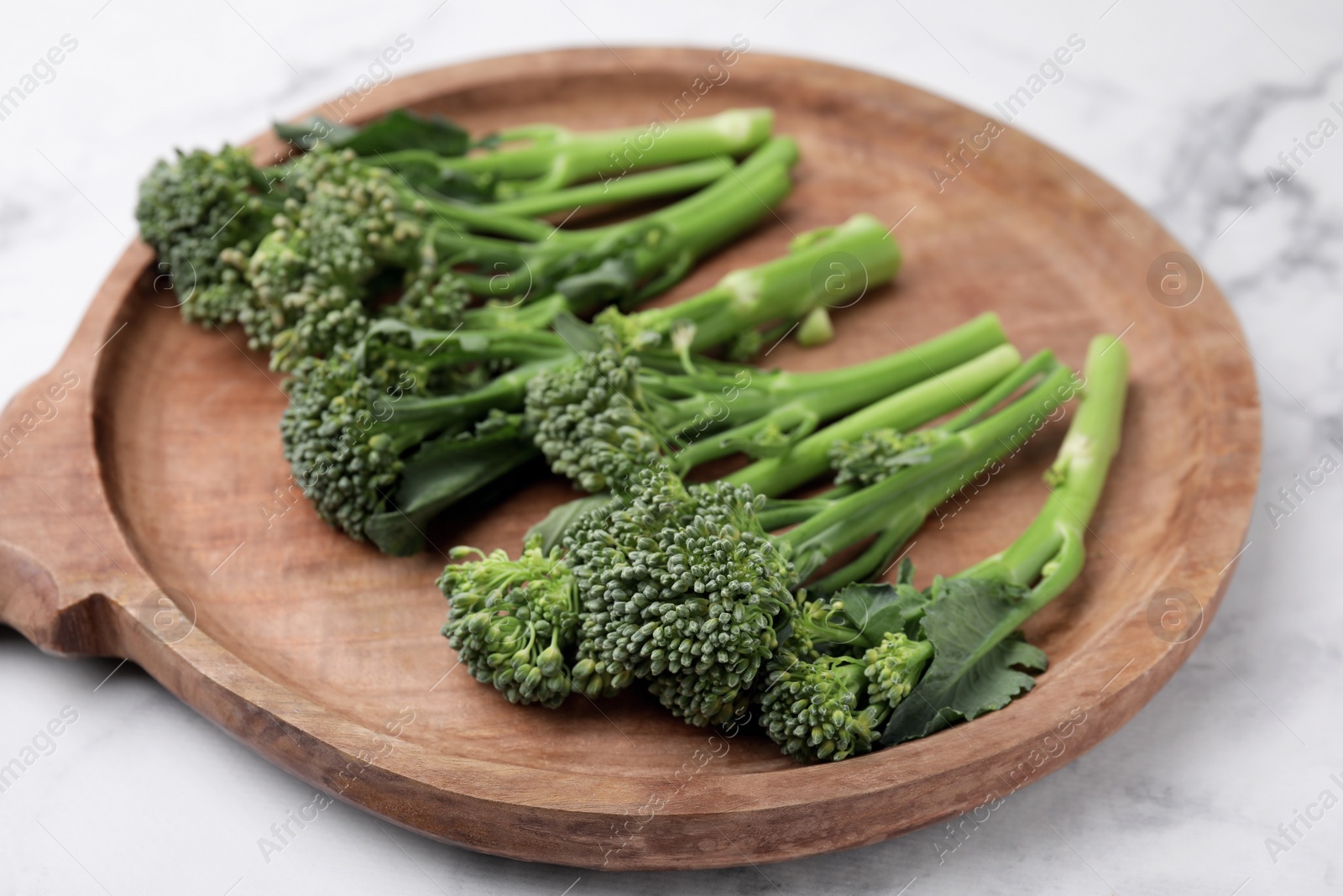 Photo of Fresh raw broccolini on white marble table, closeup. Healthy food