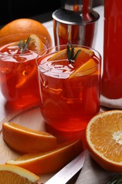 Photo of Aperol spritz cocktail, ice cubes, rosemary and orange slices in glasses on table, closeup