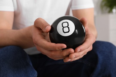 Man holding magic eight ball indoors, closeup