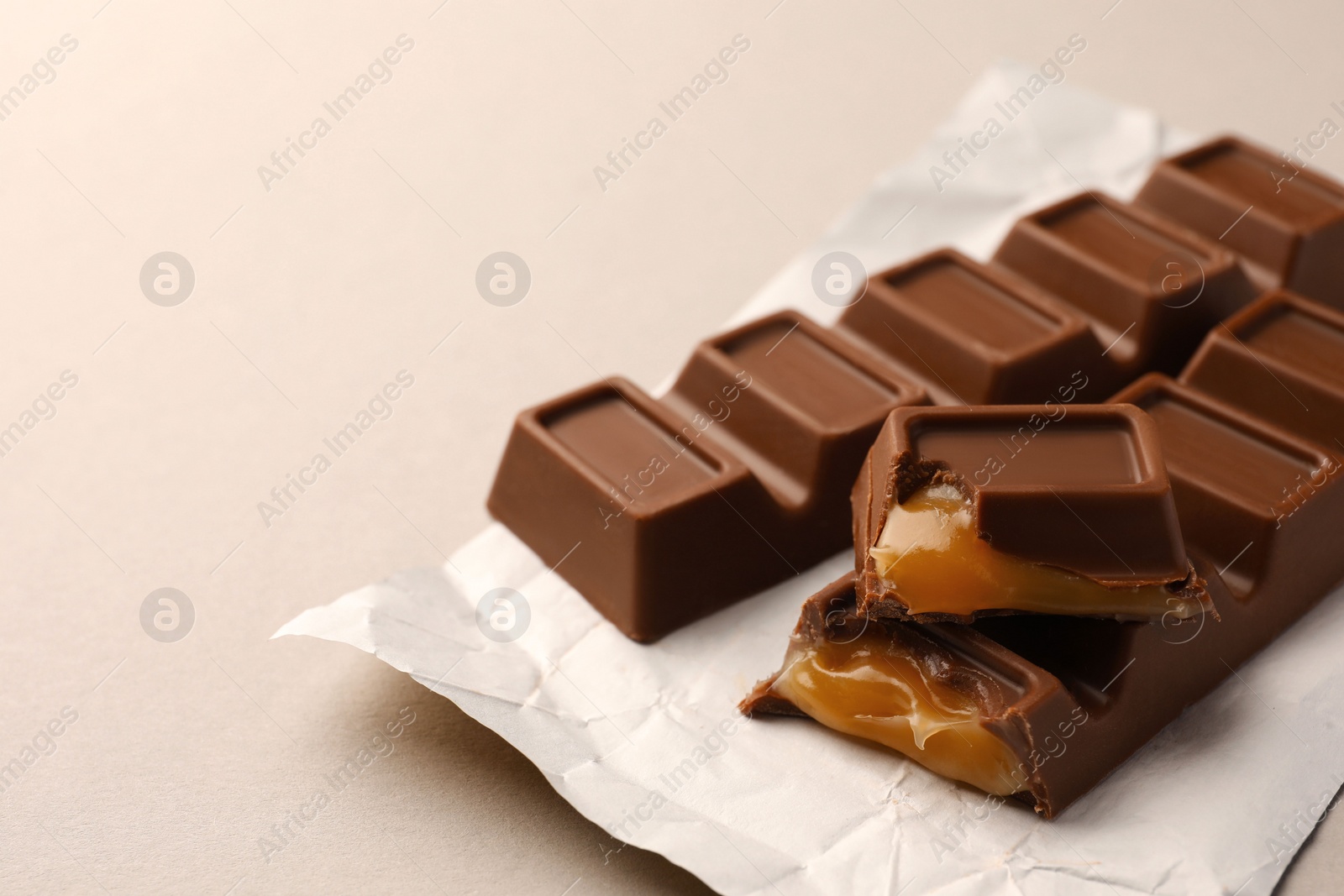 Photo of Tasty chocolate bars with paper wrap on light background, space for text