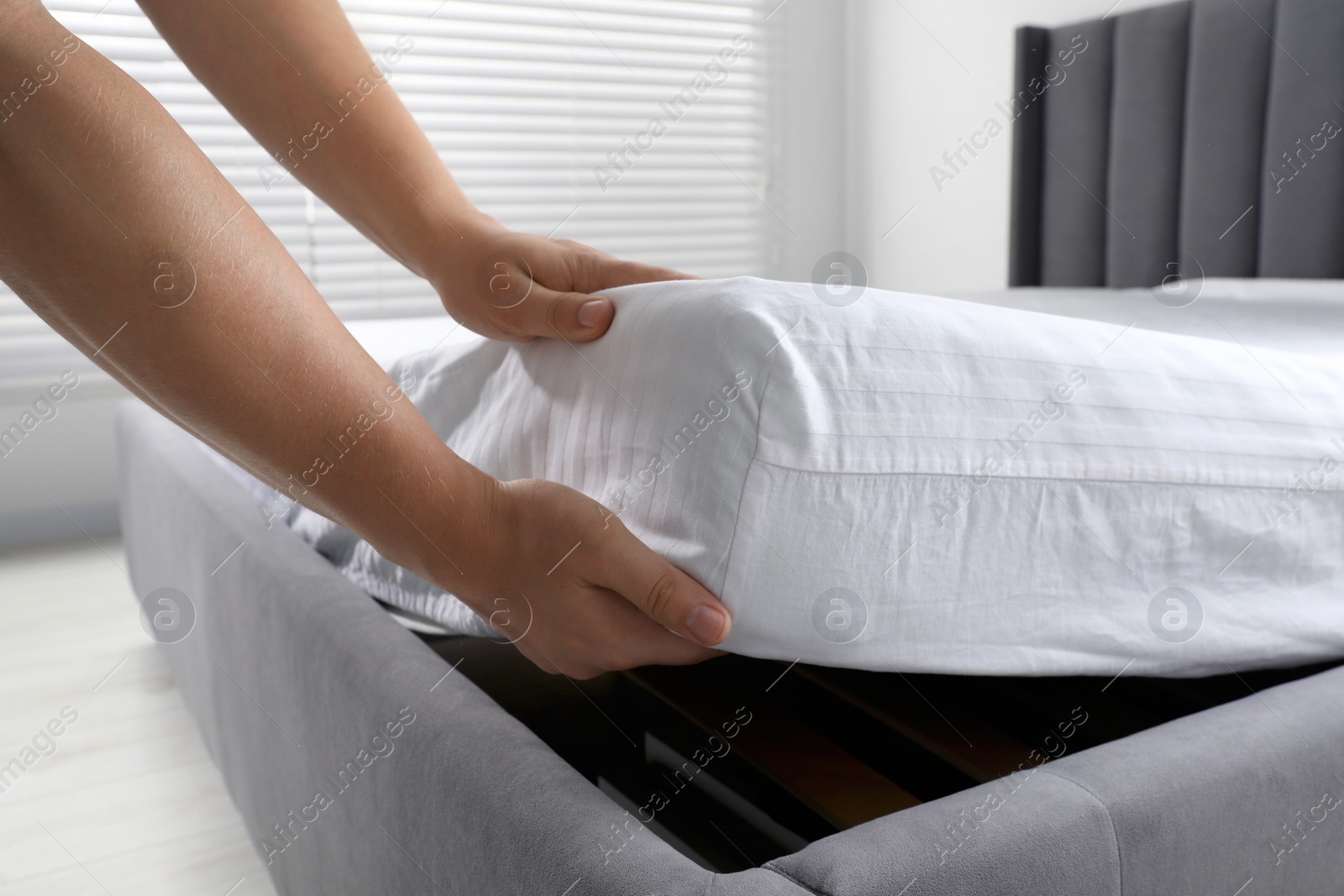 Photo of Woman covering mattress with protector indoors, closeup