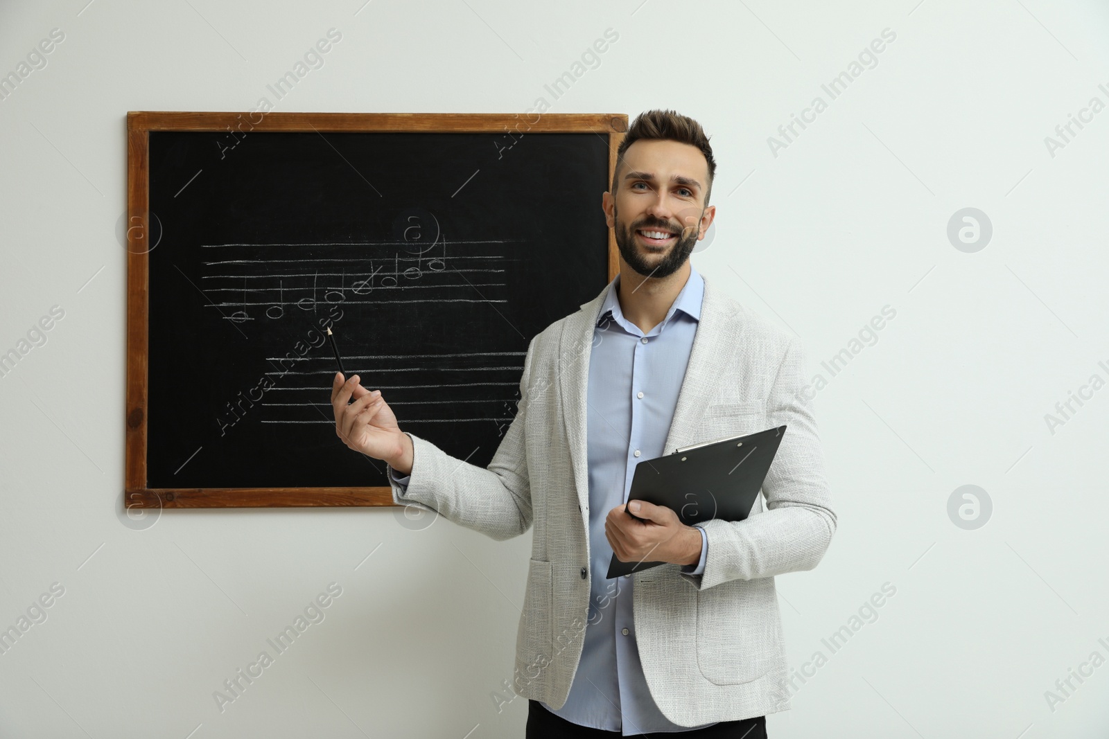 Photo of Teacher near black chalkboard with music notes in classroom