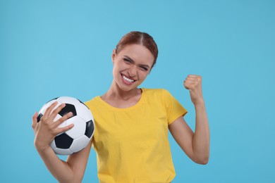 Photo of Emotional fan holding football ball and celebrating on light blue background