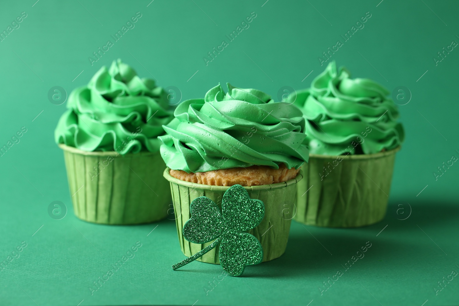 Photo of St. Patrick's day party. Tasty cupcakes on green background, closeup