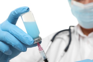 Doctor filling syringe with medication from glass vial on white background, closeup