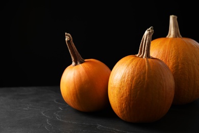 Photo of Ripe pumpkins on grey table against black background. Holiday decoration
