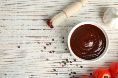 Flat lay composition with barbecue sauce on white wooden table. Space for text