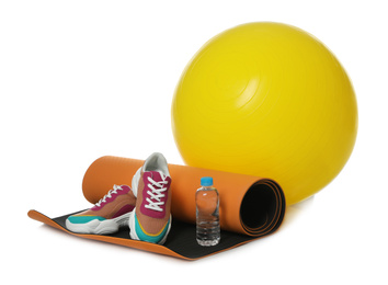 Photo of Fitness ball, yoga mat, bottle of water and sneakers isolated on white