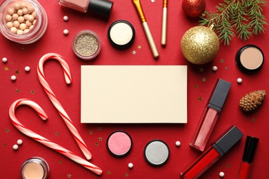 Photo of Flat lay composition with makeup products, empty card for design and Christmas decor on background