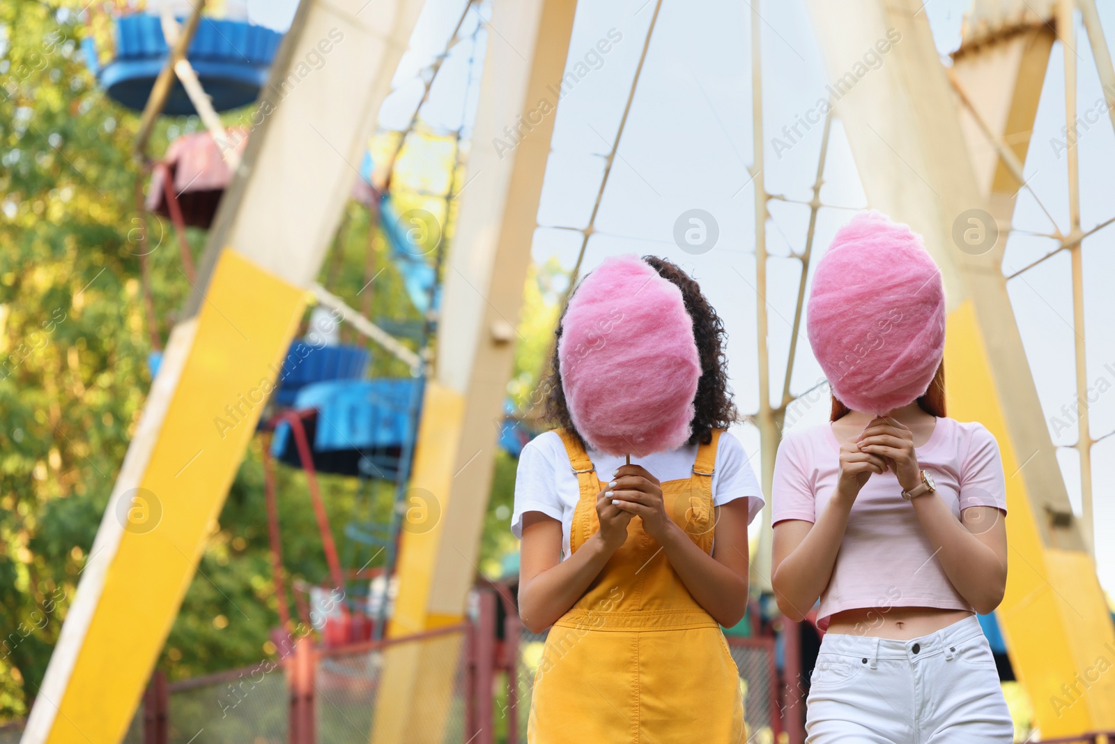 Photo of Women covering faces with cotton candies outdoors. Space for text