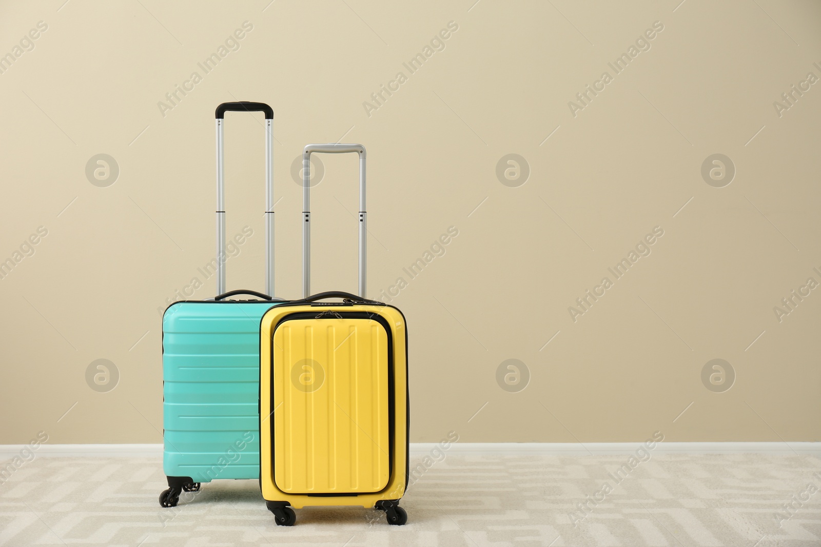 Photo of Modern suitcases on floor near light wall. Space for text