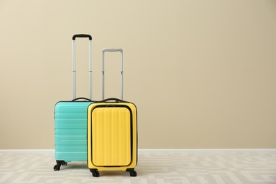 Modern suitcases on floor near light wall. Space for text