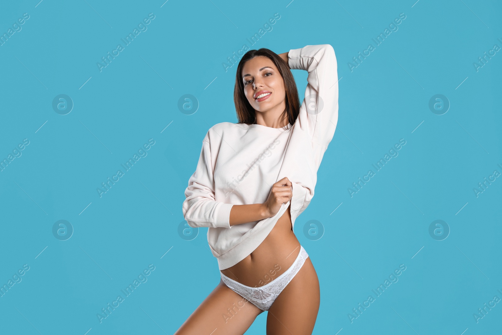 Photo of Beautiful woman in white sexy panties and sweater on light blue background