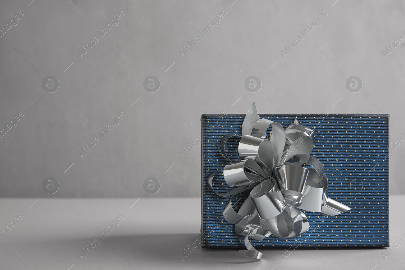 Photo of Beautiful gift box with bow on light table. Space for text