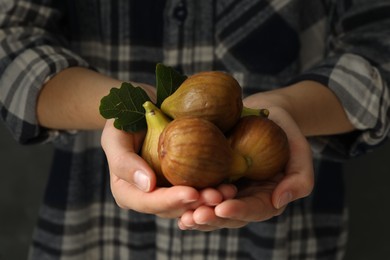 Photo of Woman holding tasty raw figs with leaf, closeup