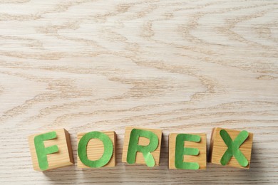 Word Forex made of green letters and cubes on wooden table, flat lay. Space for text