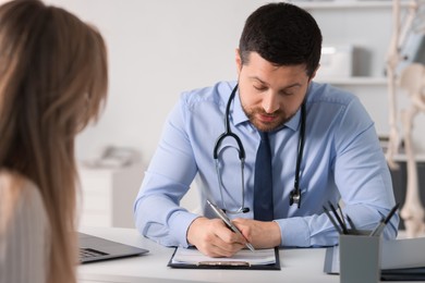 Professional doctor working with patient at white table in hospital