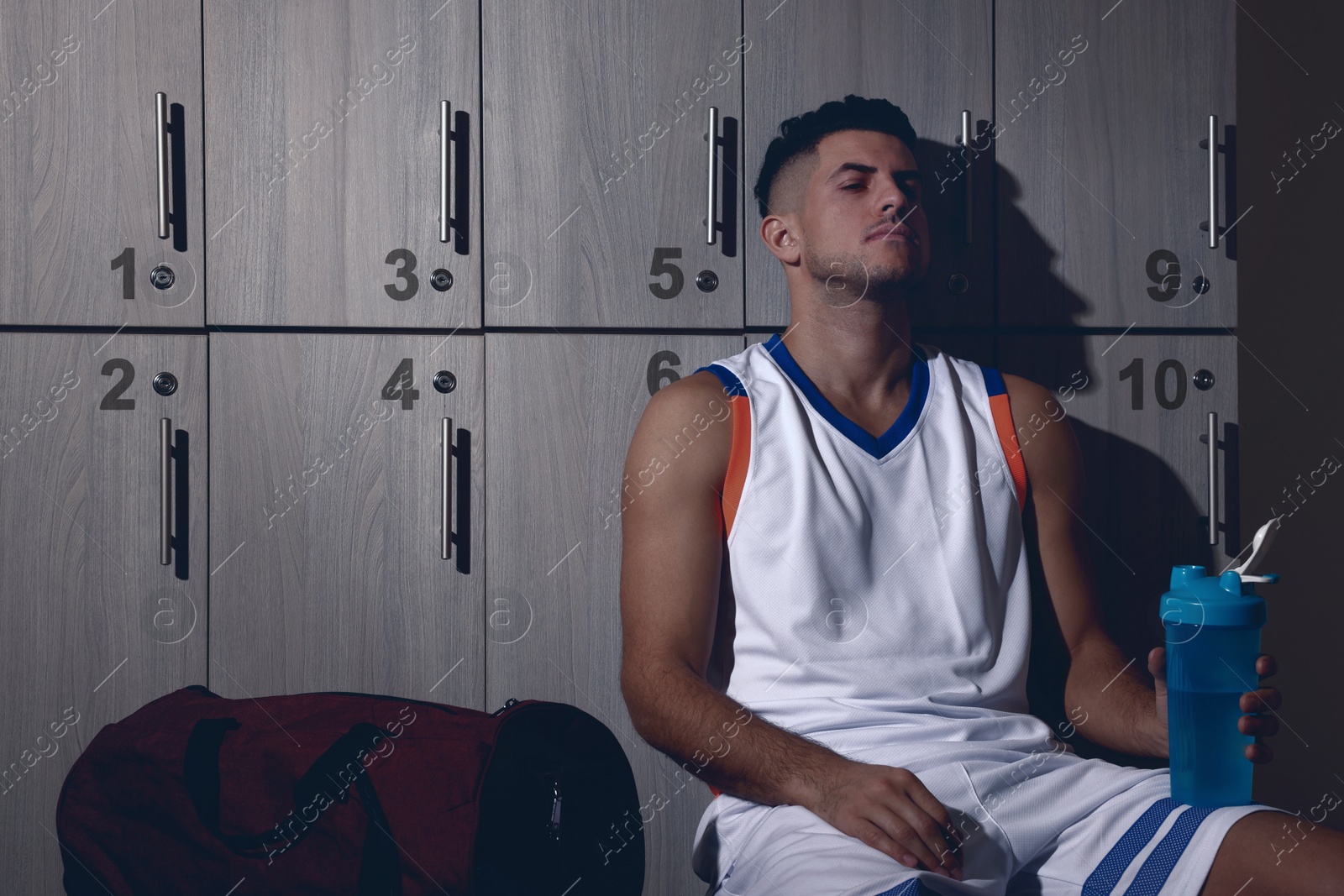 Image of Handsome tired man with shaker in locker room