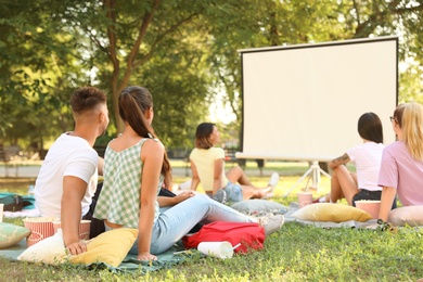 Photo of Young people watching movie in open air cinema. Space for text