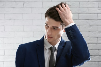 Portrait of young businessman with beautiful hair on brick wall background