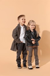 Photo of Fashion concept. Stylish children posing on pale orange background