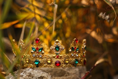 Photo of Beautiful golden crown on stone outdoors, closeup. Fantasy item