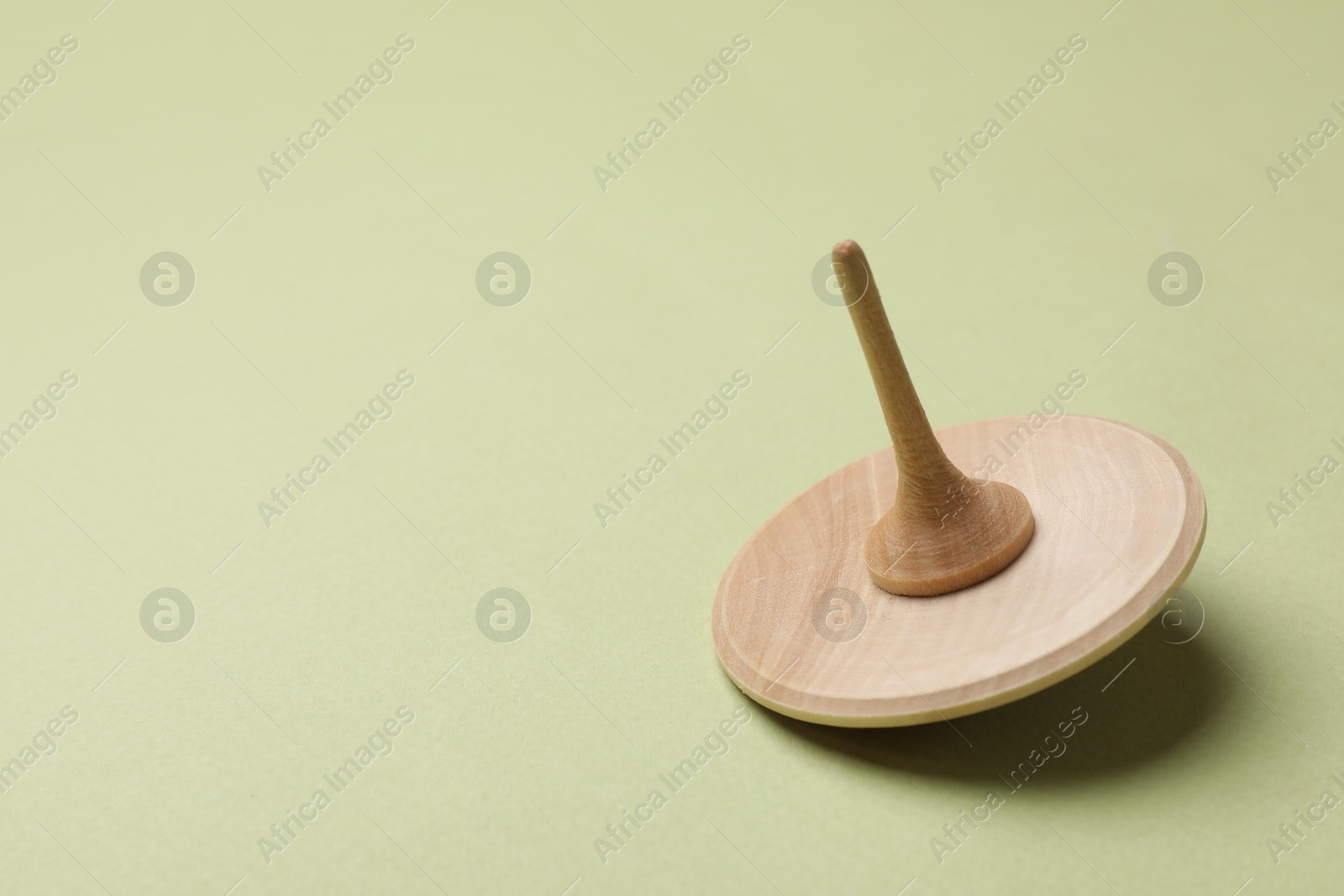 Photo of One wooden spinning top on green background, space for text