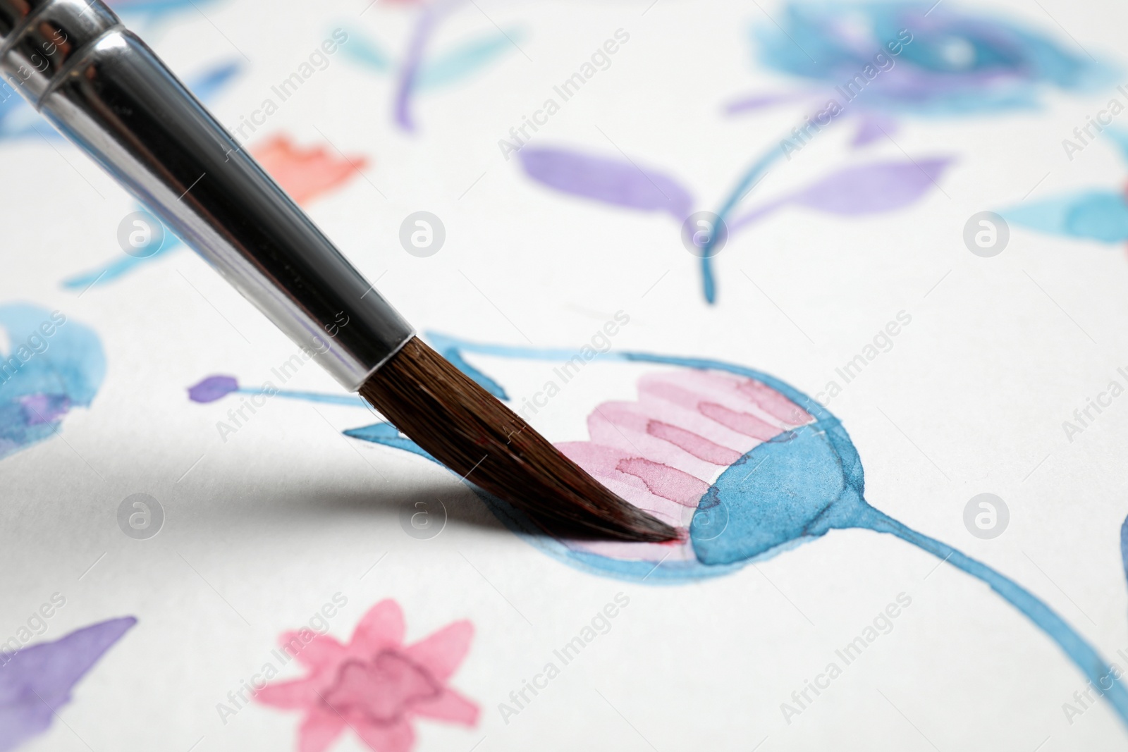 Photo of Painting flower with watercolor paint on white paper, closeup