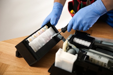 Repairman with screwdriver fixing modern printer, closeup